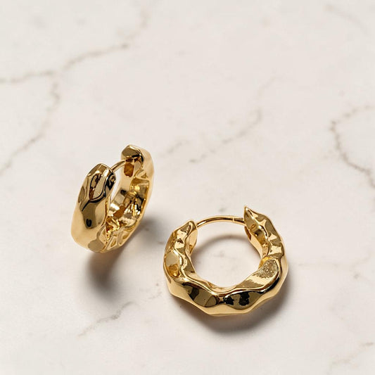 Gold hoop earrings on a light marble background