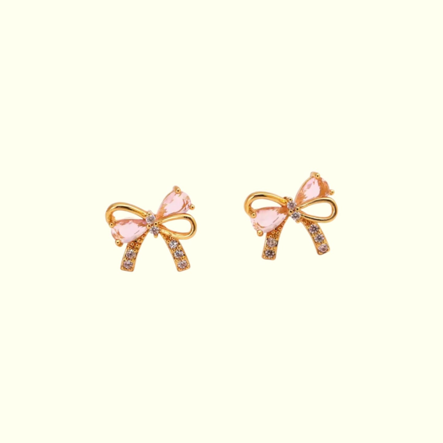 Bow-shaped earrings with pink centers and gold accents on a white background