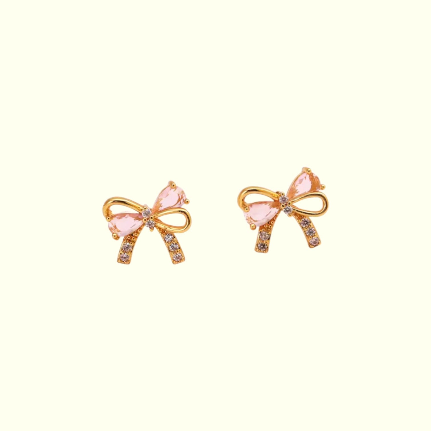 Bow-shaped earrings with pink centers and gold accents on a white background