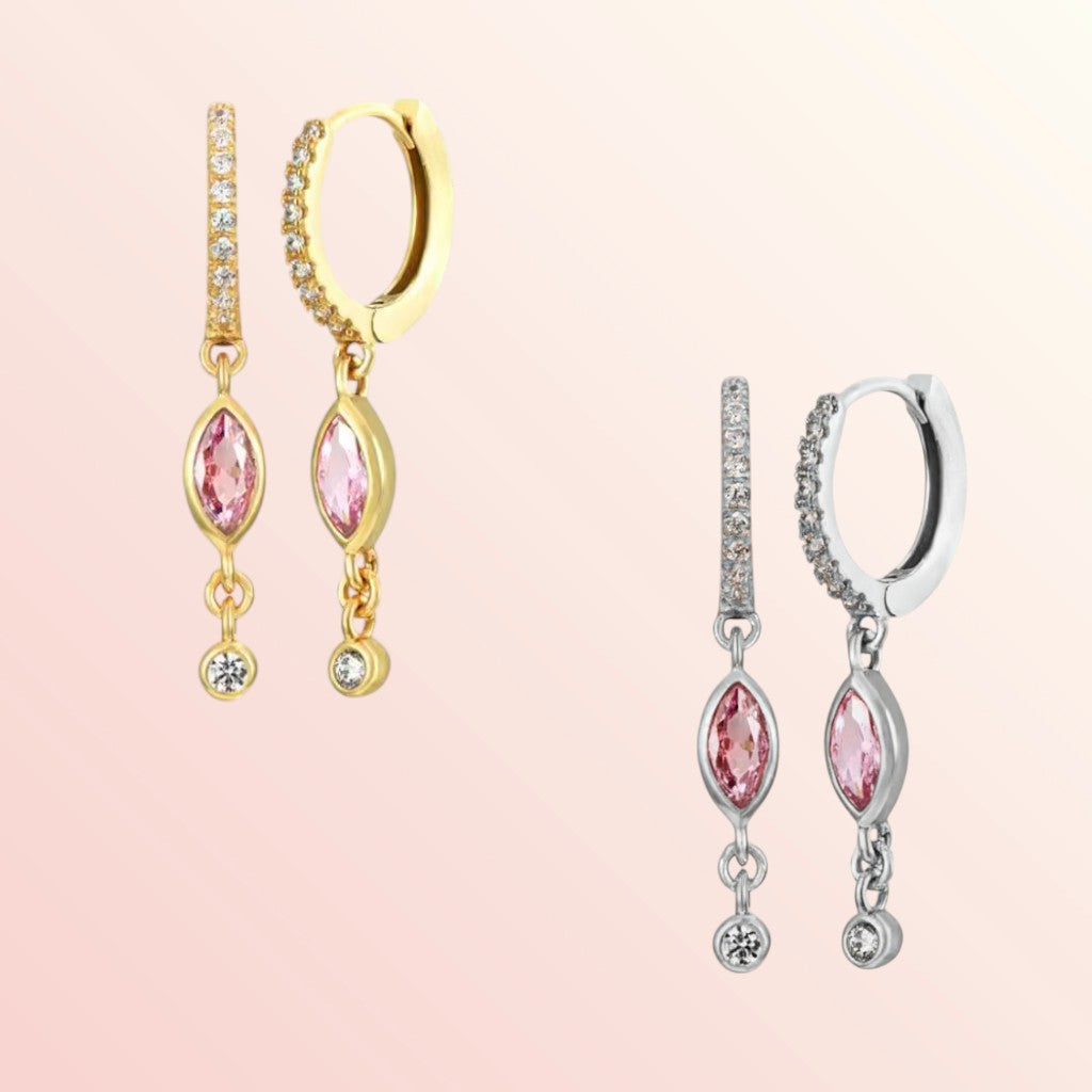 Pair of gold and silver earrings with pink gemstones on a light pink background
