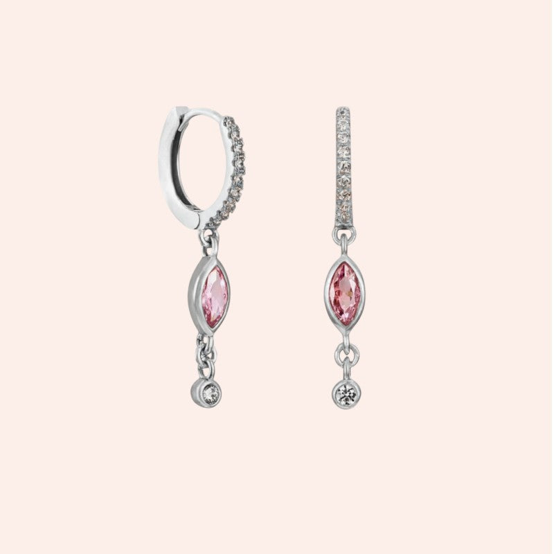 Silver earrings with pink gemstones on a light pink background