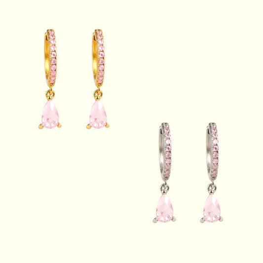 Pair of gold hoop earrings with pink teardrop-shaped gemstones on a white background
