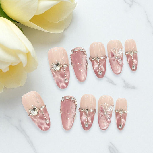 Set of pink nail art with rhinestones on a white surface with yellow tulips.