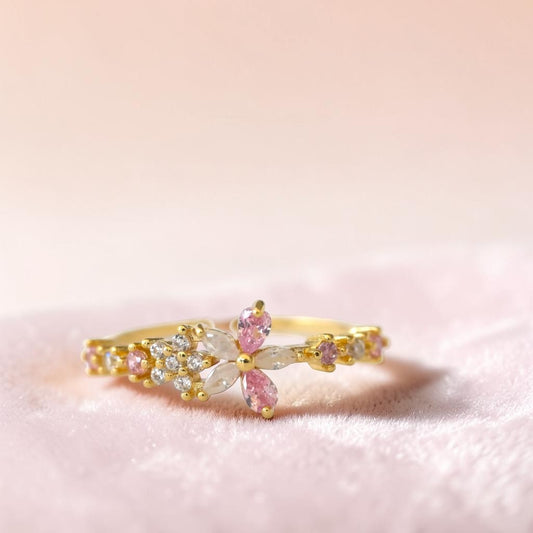 Gold ring with pink gemstones on a pink background