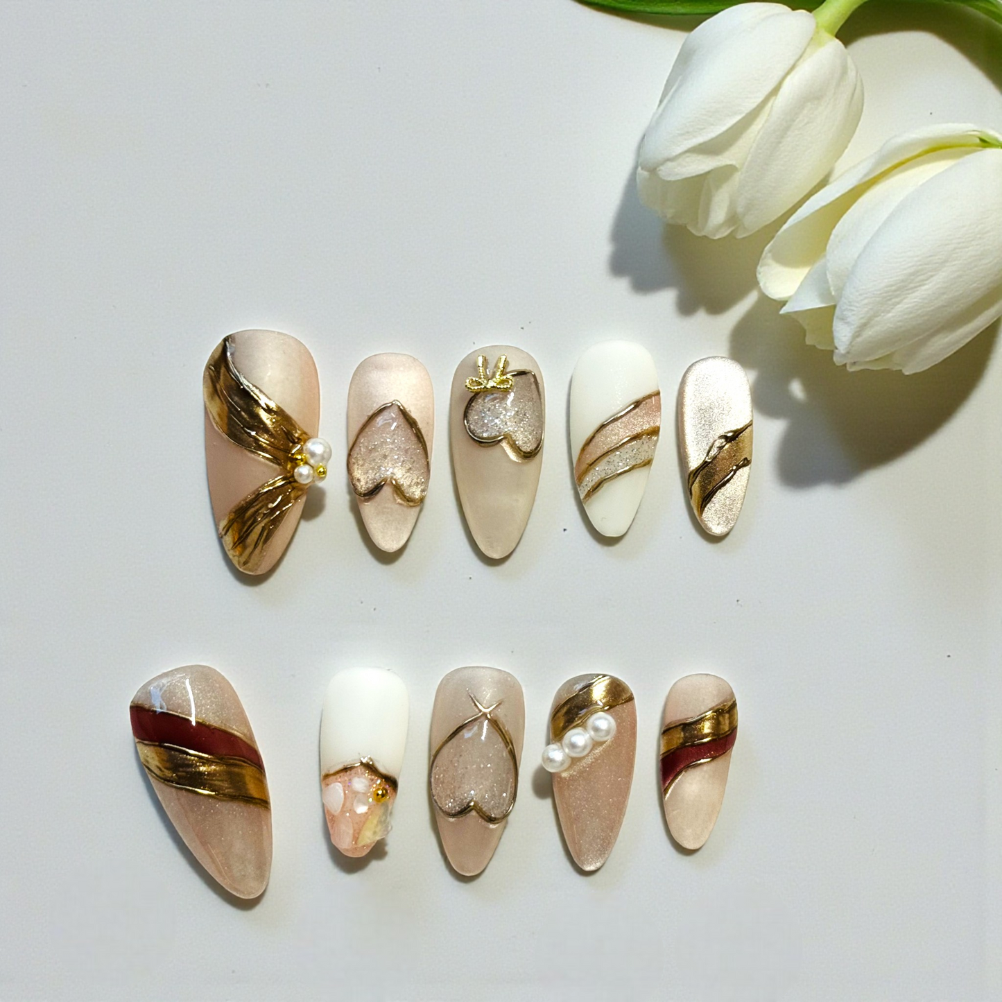 Set of decorative nail art designs on a white surface with white tulips.
