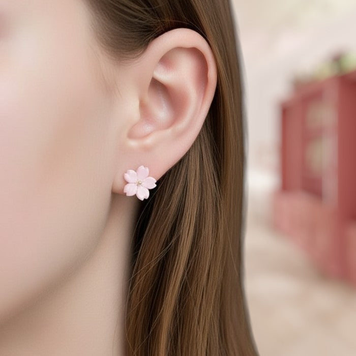 Close-up of a person wearing pink flower earrings with a blurred background