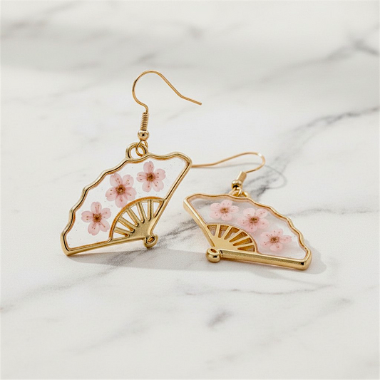 Gold earrings with floral design on a marble surface