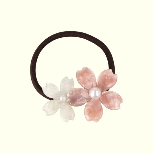 Hair elastic with pink and white floral decorations on a white background