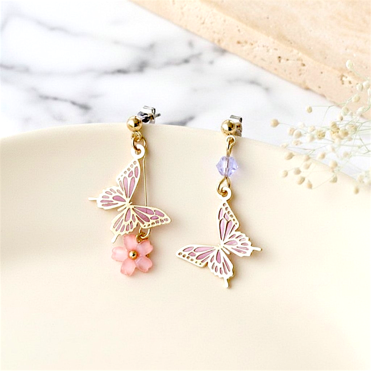 Butterfly-shaped earrings with pink flowers on a marble surface