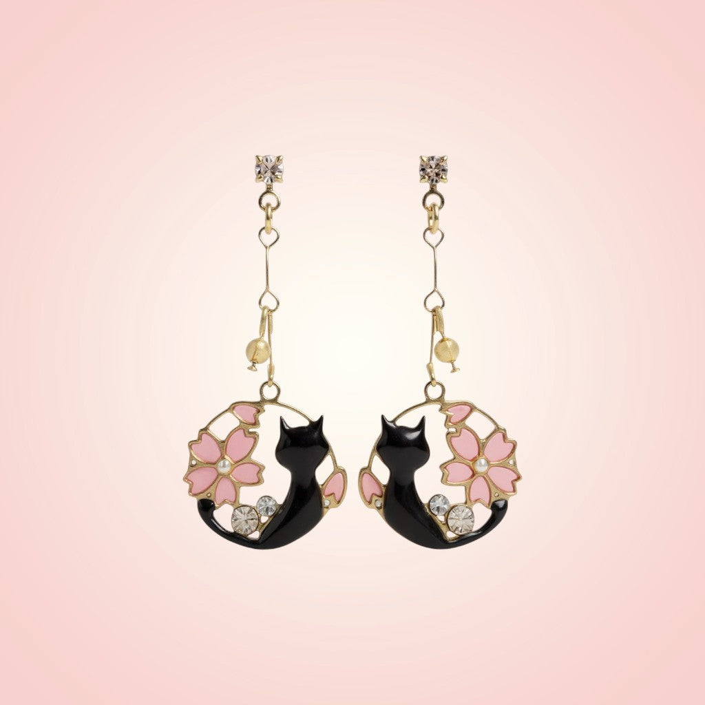 Pair of cat-shaped earrings with floral designs on a pink background