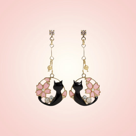 Pair of cat-shaped earrings with floral designs on a pink background