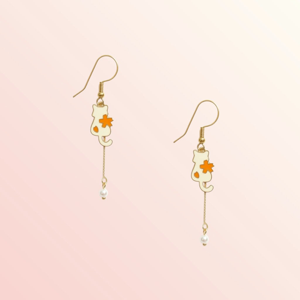 Cat-shaped earrings with flower details on a light pink background