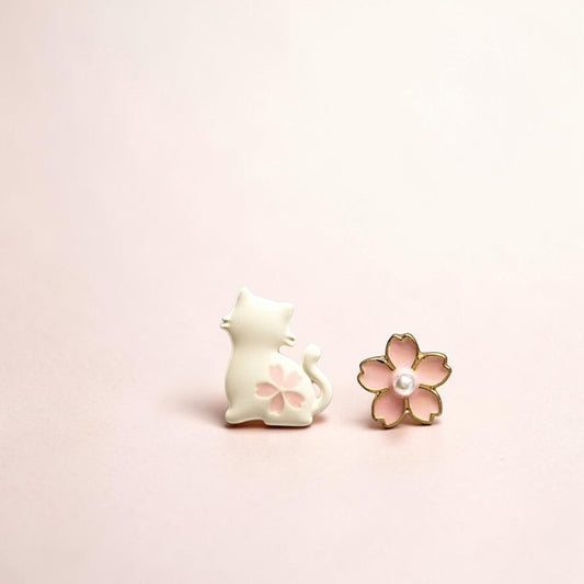 Cat-shaped earring and flower-shaped earring on a light pink background