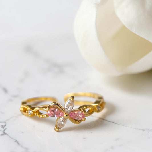Gold ring with pink gemstones on a marble surface