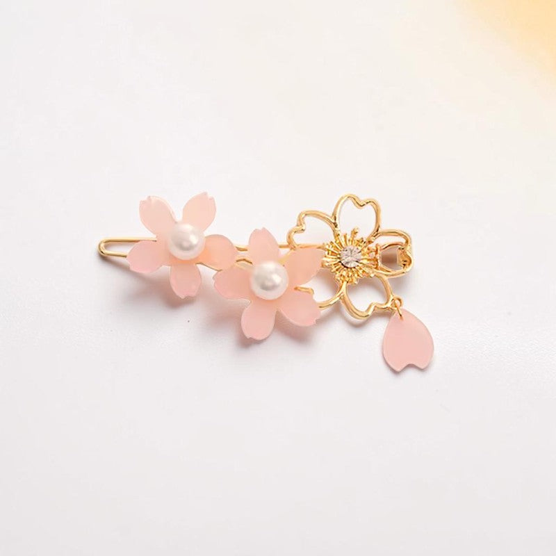 Floral hair clip with pink flowers and gold accents on a light background