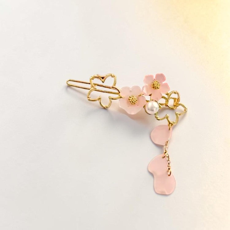 Decorative hair clip with pink flowers and gold accents on a light background