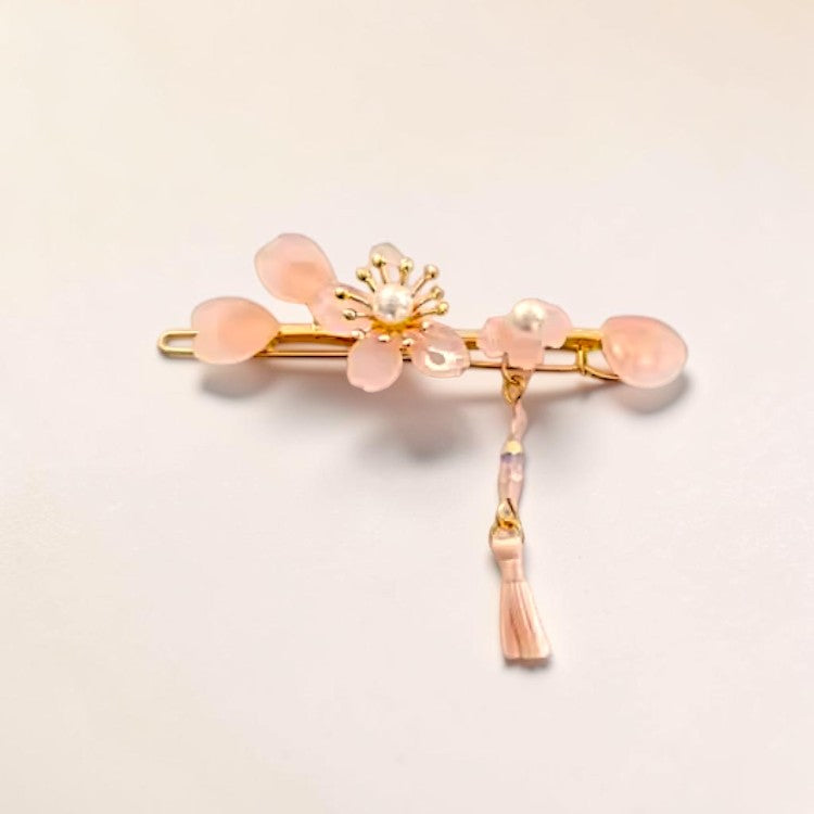 Decorative hair clip with pink stones and gold accents on a light beige background