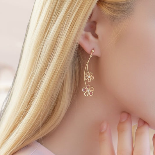 Close-up of a woman wearing a gold floral earring with a pink gemstone.