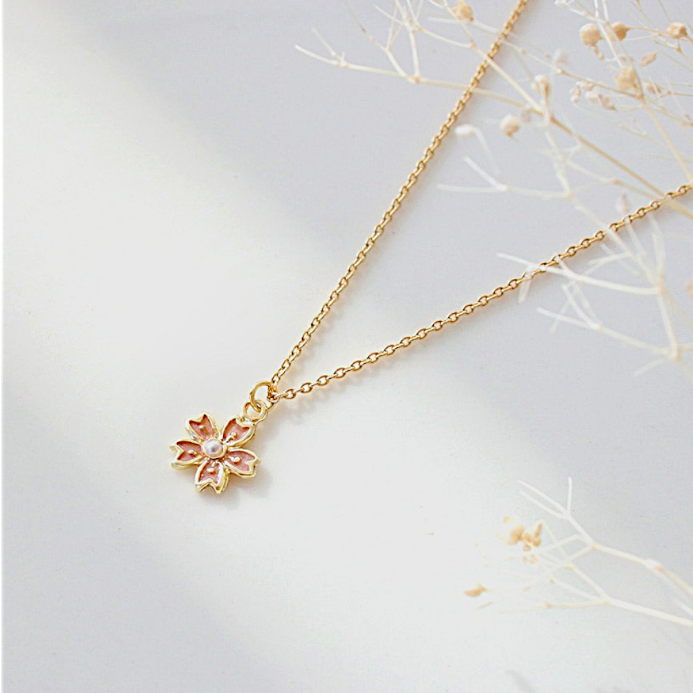 Gold necklace with a floral pendant on a light gray background