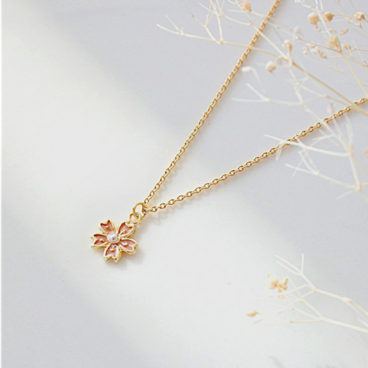 Gold necklace with a floral pendant on a light gray background