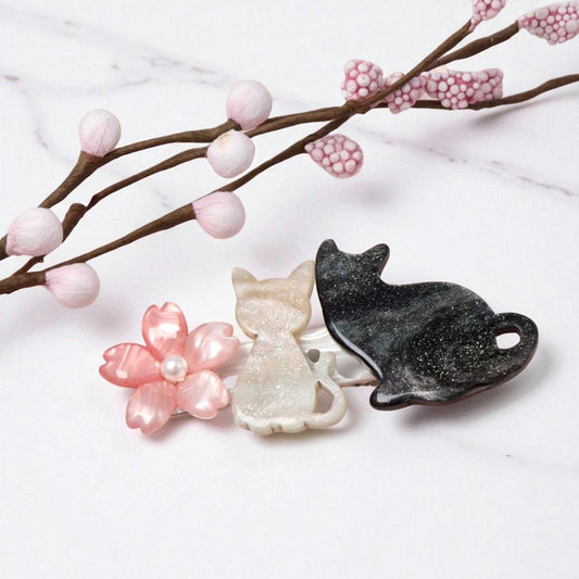 Three decorative items shaped like a flower, cat, and leaf on a white background with pink flowers.