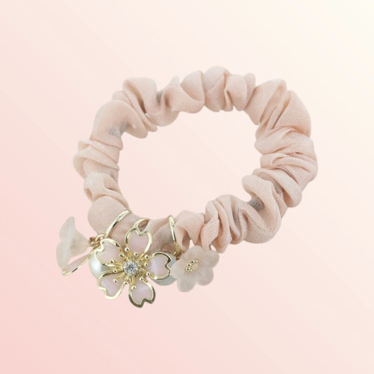 Pink scrunchie with floral charm on a pink background
