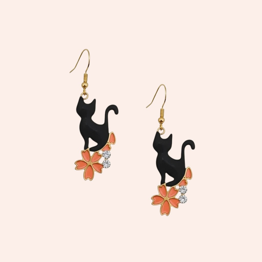Black cat earrings with floral designs on a beige background