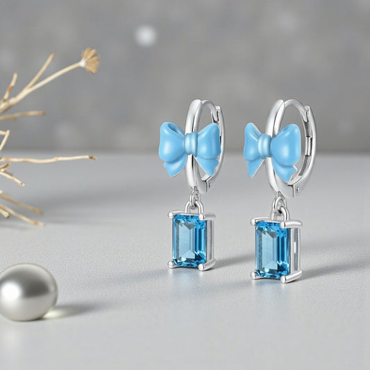 Earrings with blue bow and gemstones on a gray background