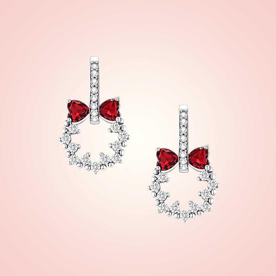 Pair of earrings with red gemstones on a pink background
