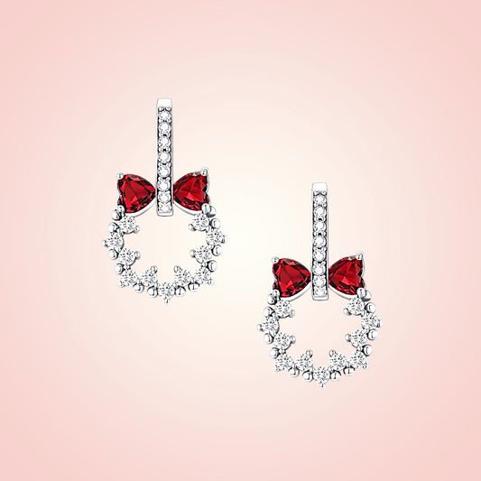 Pair of earrings with red gemstones on a pink background