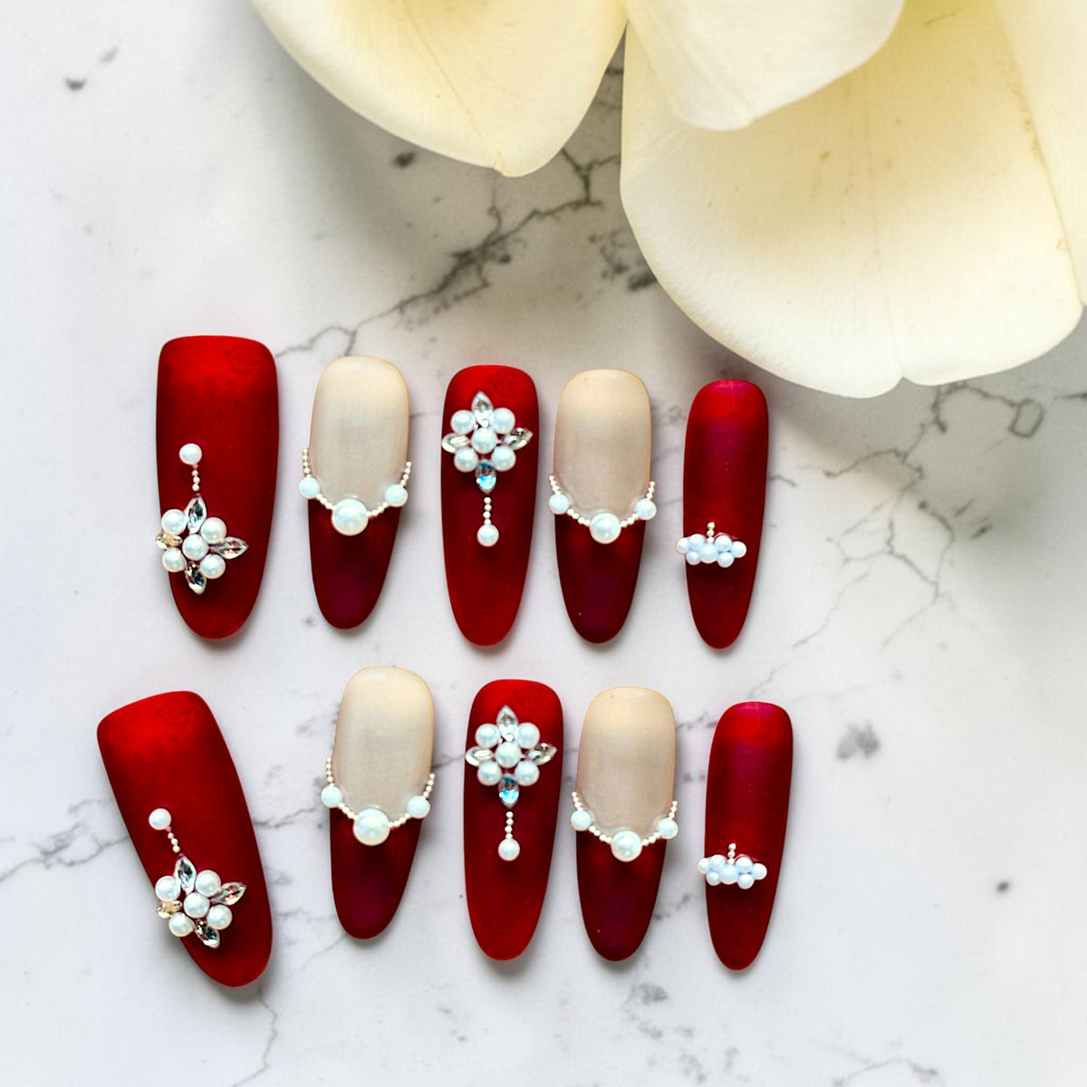 Luxury handmade crimson red and ivory press-on nails featuring pearl floral embellishments, sparkling crystal accents, and elegant long nail tips by Bows and Knots Co.