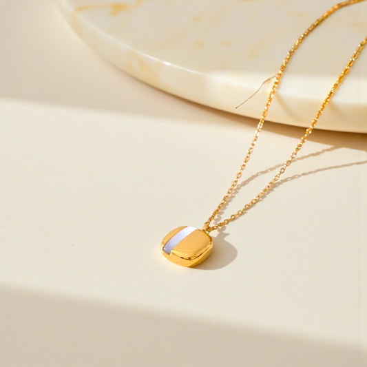 Gold necklace with a heart-shaped pendant on a beige background