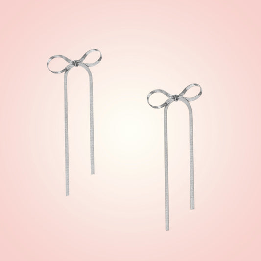 Pair of silver bow earrings on a gradient pink background