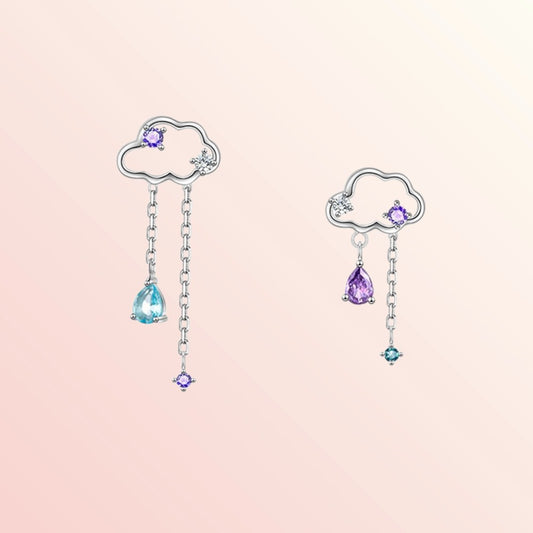 Pair of cloud-shaped earrings with gemstone drops on a pink background