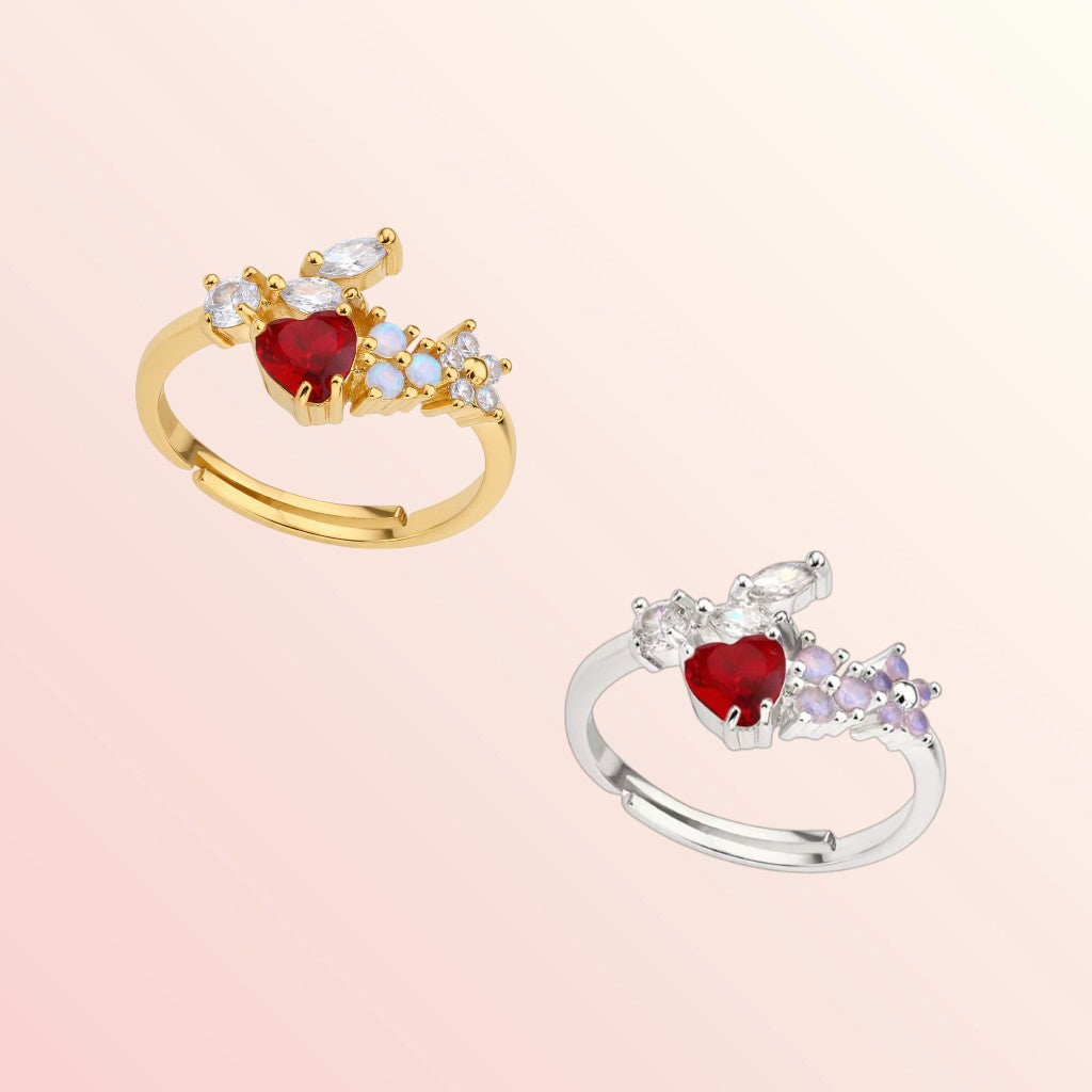 Two rings with red gemstones and gold and silver bands on a light pink background