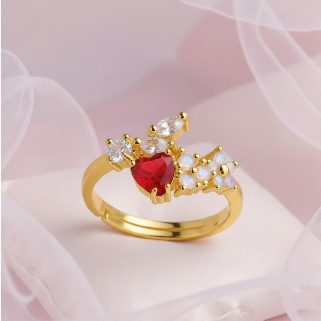 Gold ring with a red gemstone and white stones on a soft pink background