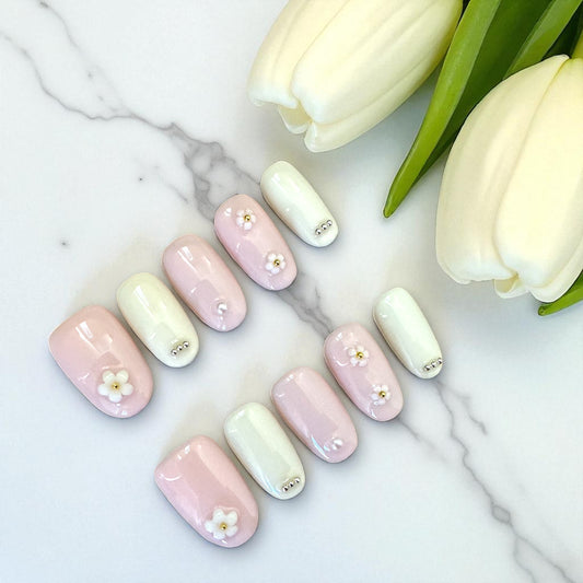 Pastel-colored nail art with floral designs on a marble surface with tulips.