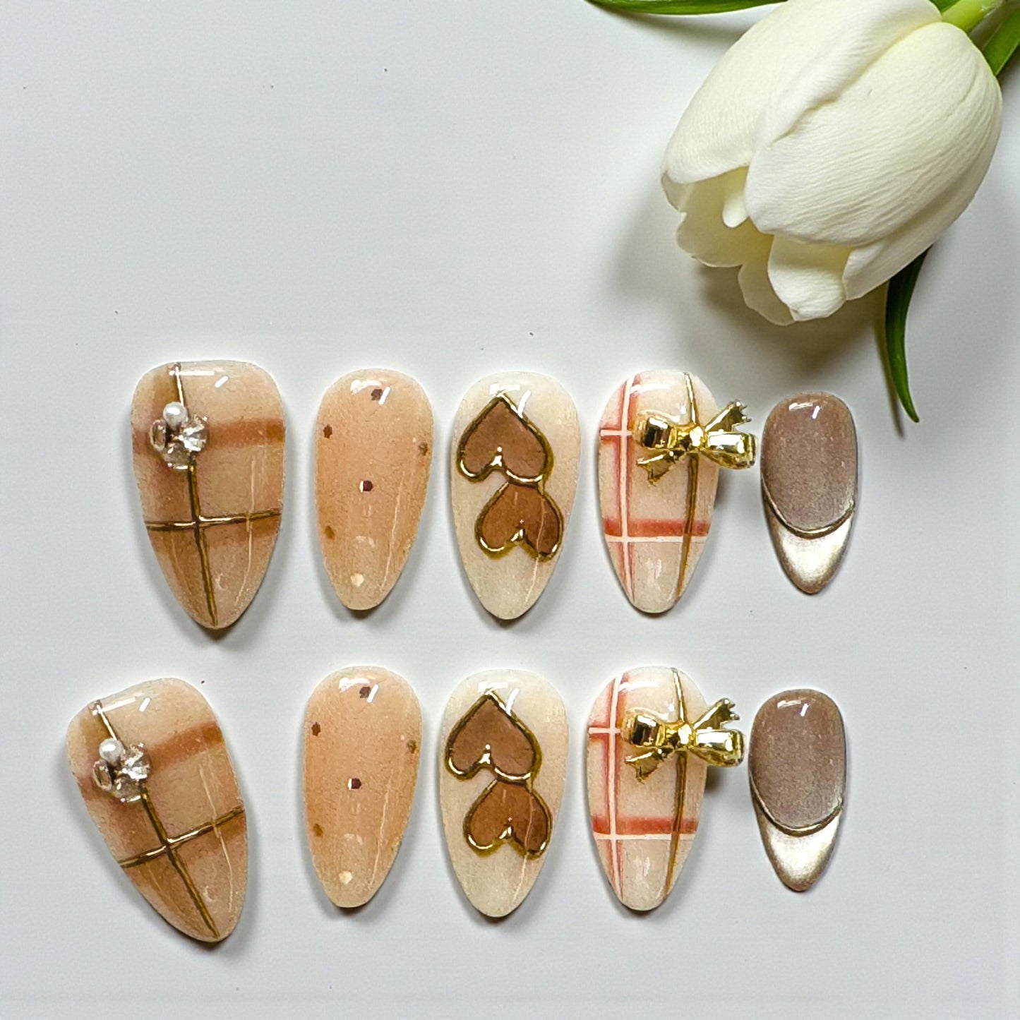 Set of nail art designs on a white surface with a white tulip.
