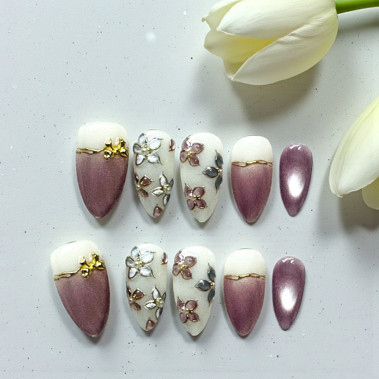 Decorative nail art designs on nails with a white tulip in the background