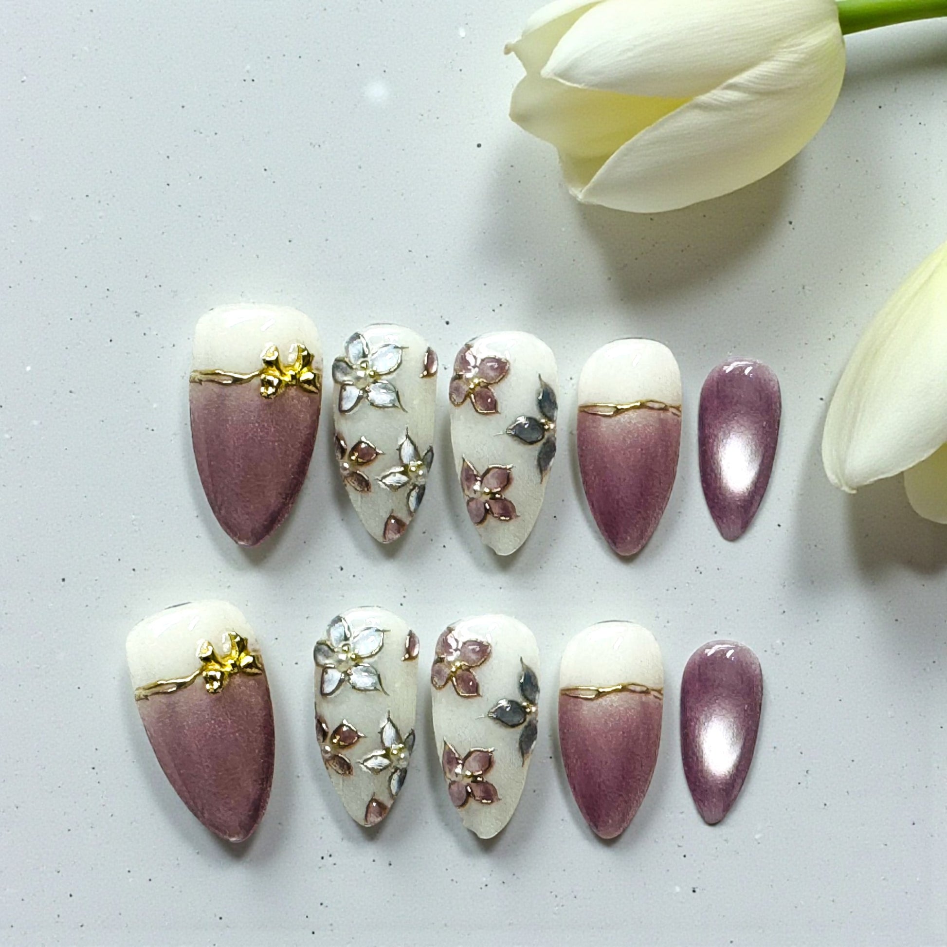 Decorative nail art designs on nails with a white tulip in the background