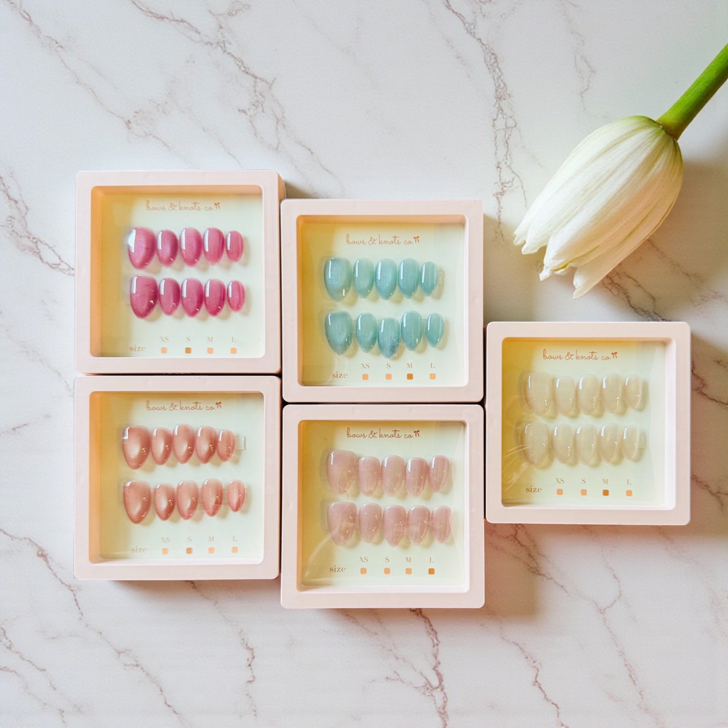 Set of press on nails with different colored options on a marble surface.