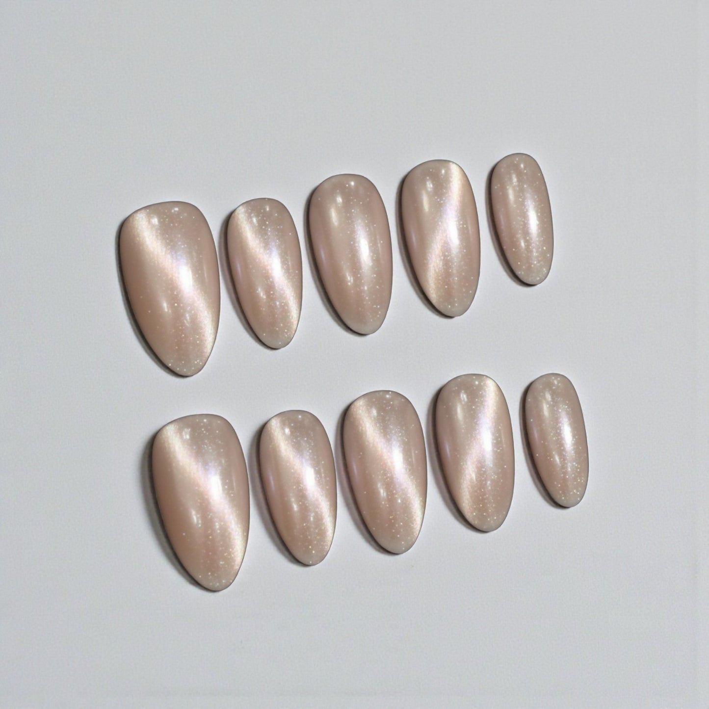 Row of beige nail polish samples on a light gray background