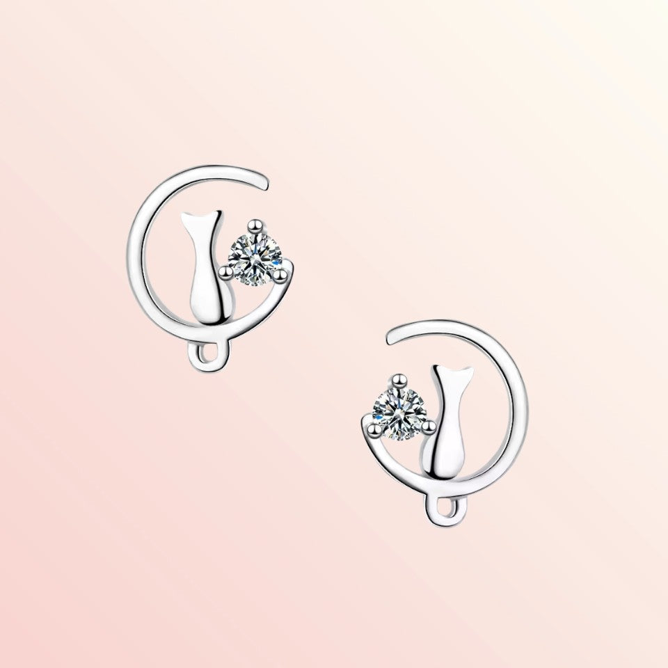 Silver earrings with clear gemstones on a pink background