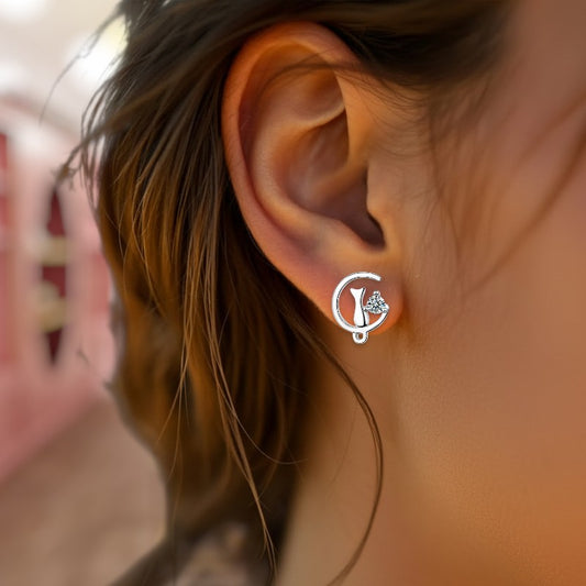Close-up of an ear wearing a silver earring with a cat sitting on a moon.