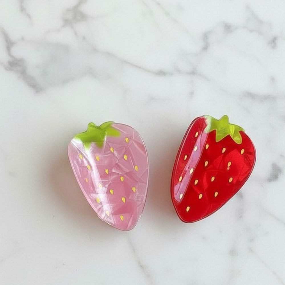 Two strawberry-shaped items on a marble surface