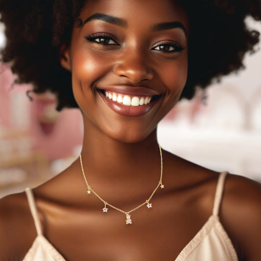 Woman wearing a gold necklace with star pendants against a blurred floral background