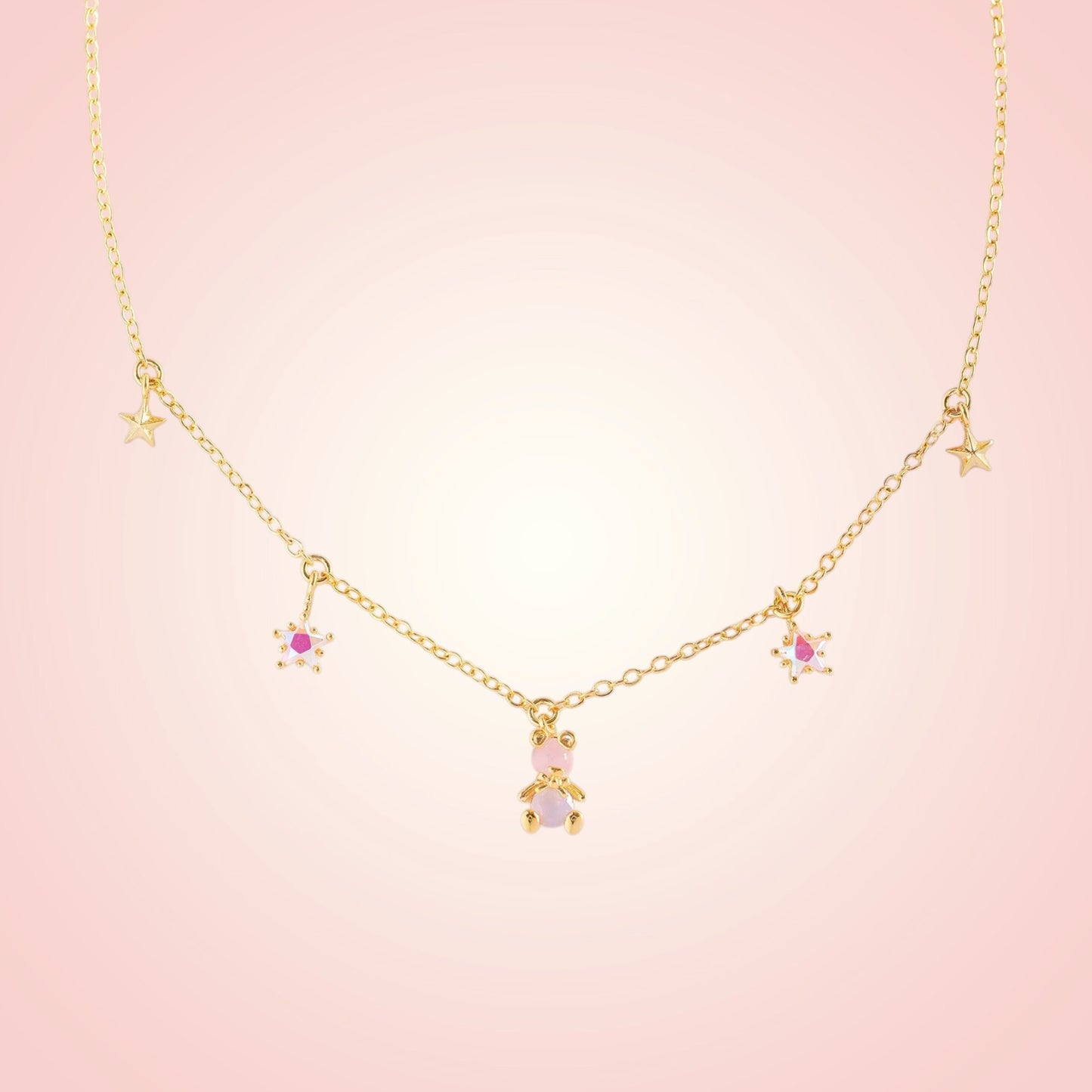 Gold necklace with star and heart pendants on a pink background