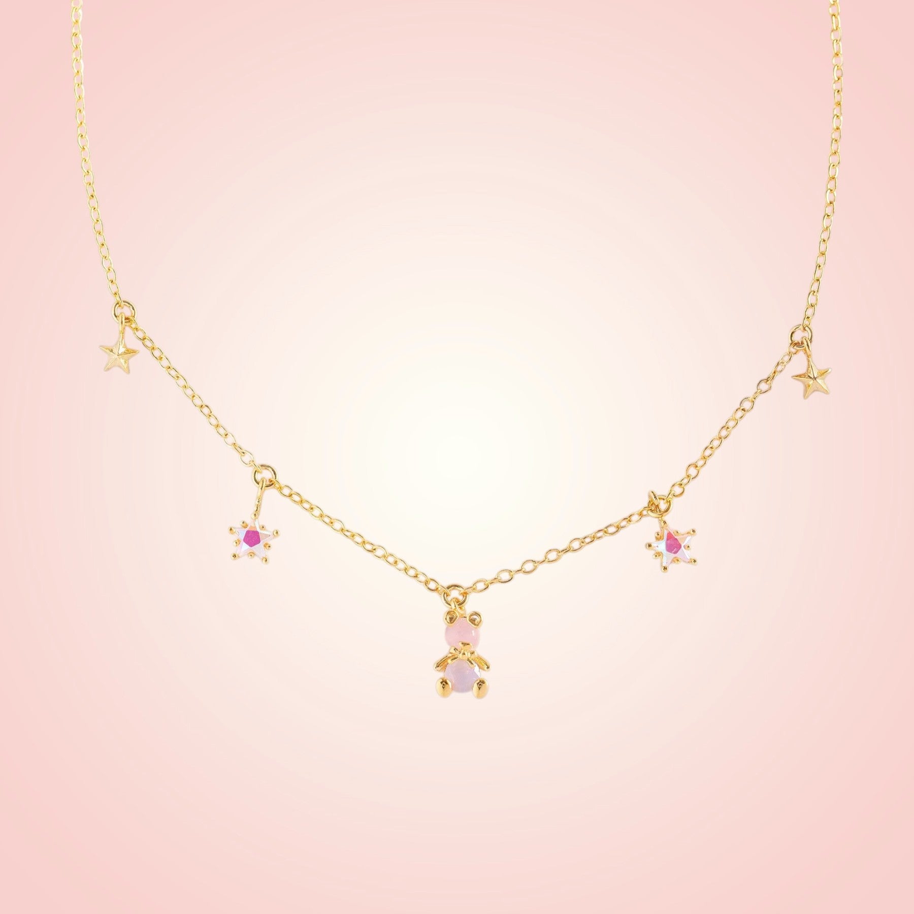 Gold necklace with star and heart pendants on a pink background