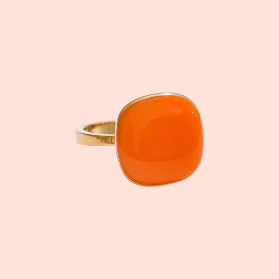Orange ring with gold band on a beige background