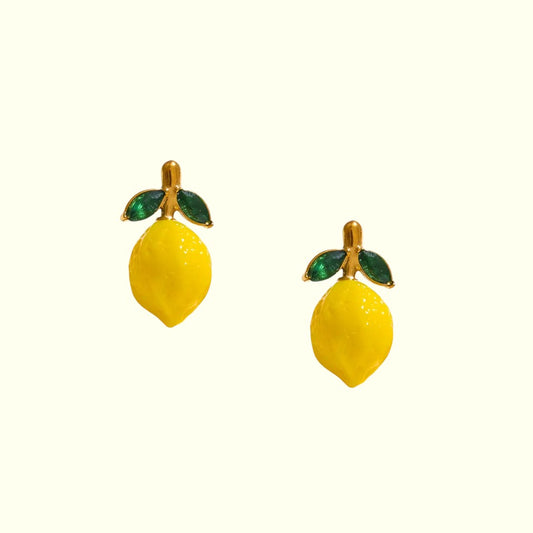 Lemon-shaped earrings with green leaves on a white background
